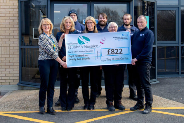 8 people holding a cheque for £822