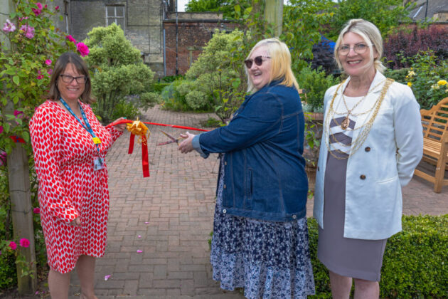 Three people cutting an opening ribbon