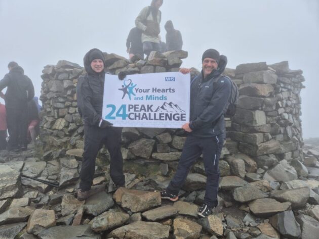 Two men holding up a sign for the 24 peaks practice