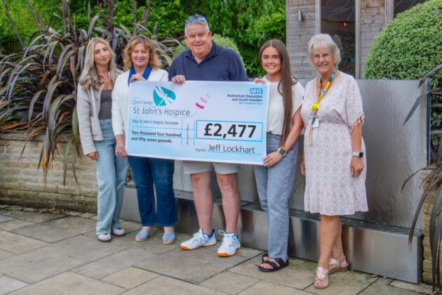 Five people holding a cheque for £2,477