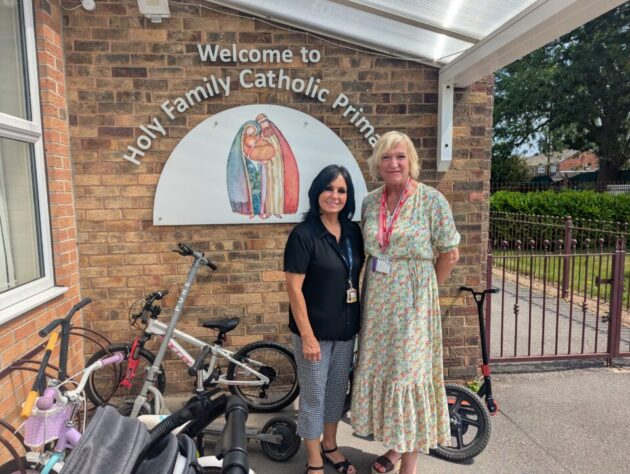 Two people stood in front of a primary school sign